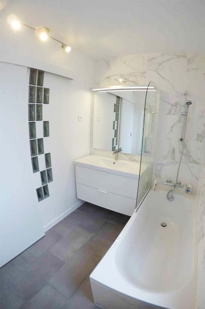 aménagement salle de bain avec carrelage façon marbre blanc et briques translucides pour éclairer les WC adjacents